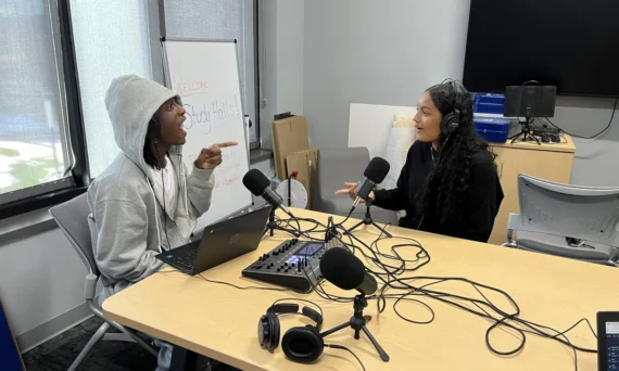 two people at a table with recording equipment